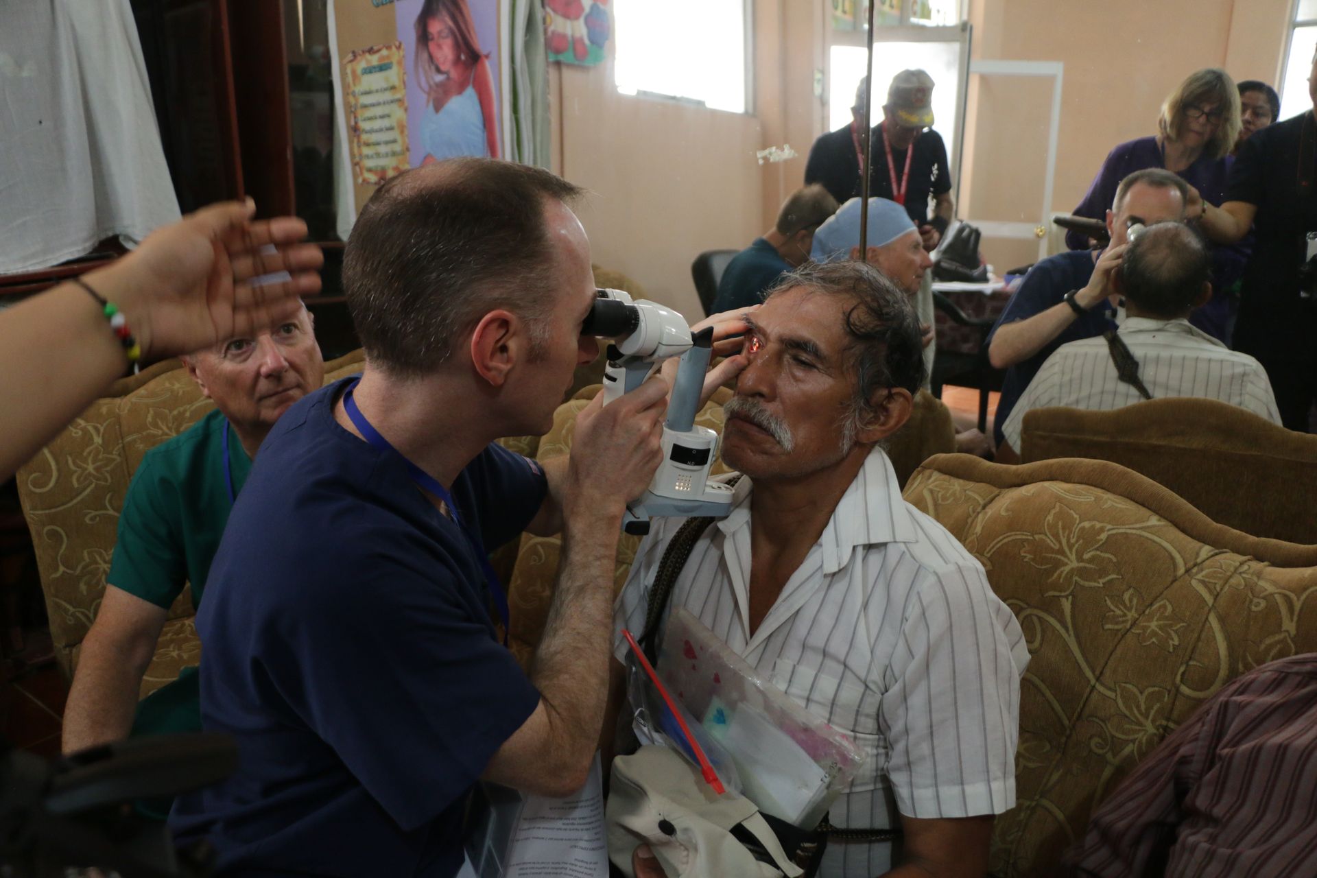 A man is looking through a microscope at another man 's eye.