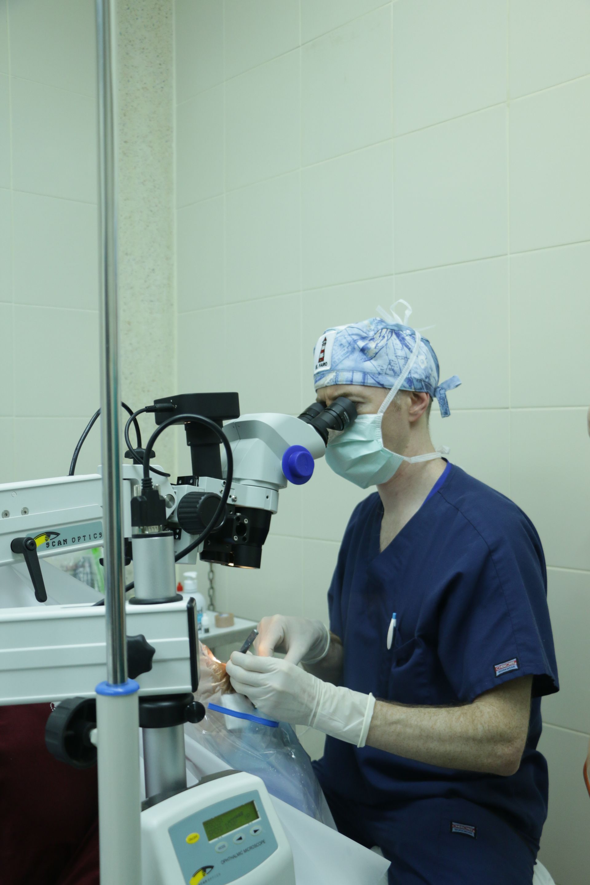 A surgeon is looking through a microscope in an operating room.