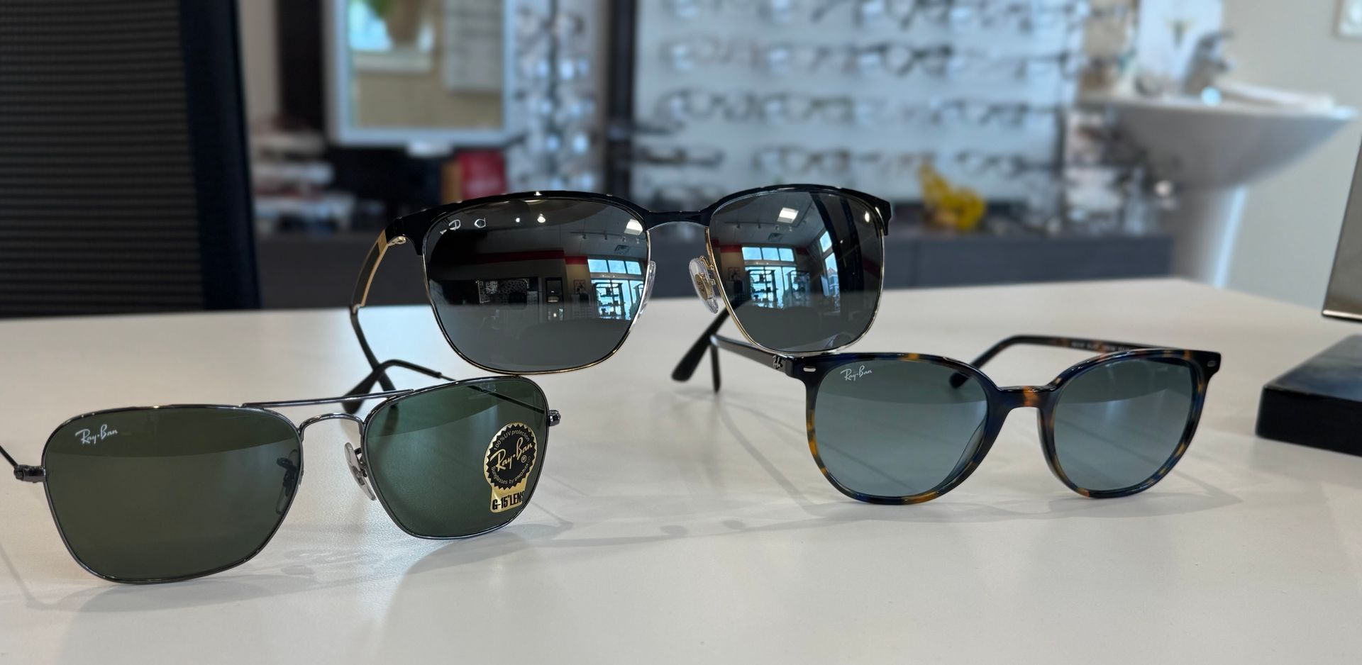 Three pairs of sunglasses are sitting on a table.