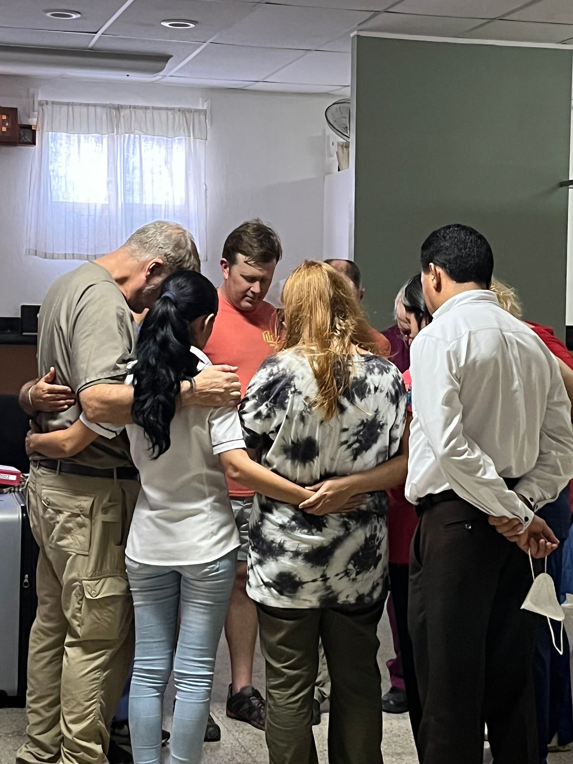 A group of people are standing in a circle with their arms around each other.