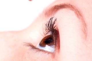 A close up of a woman 's blue eye covered in a white cloth.
