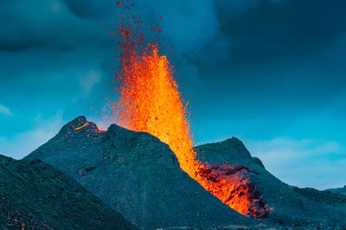 A volcano is erupting with lava coming out of it.