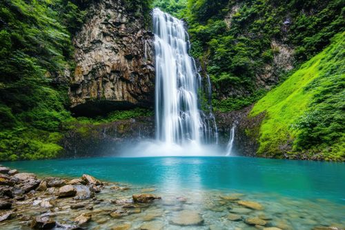 A waterfall in the middle of a forest with a blue lake in the background.