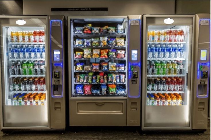Three vending machines are lined up next to each other in a room.