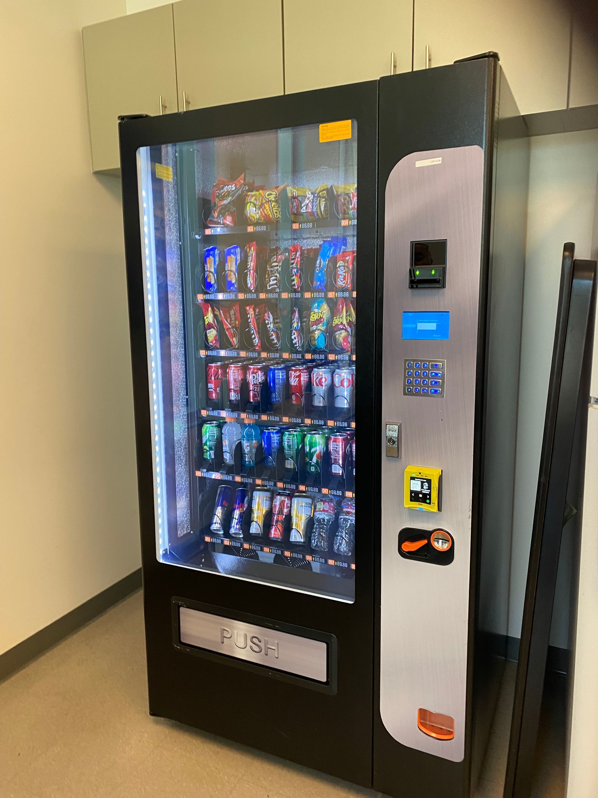 A vending machine is sitting on the floor in a room.