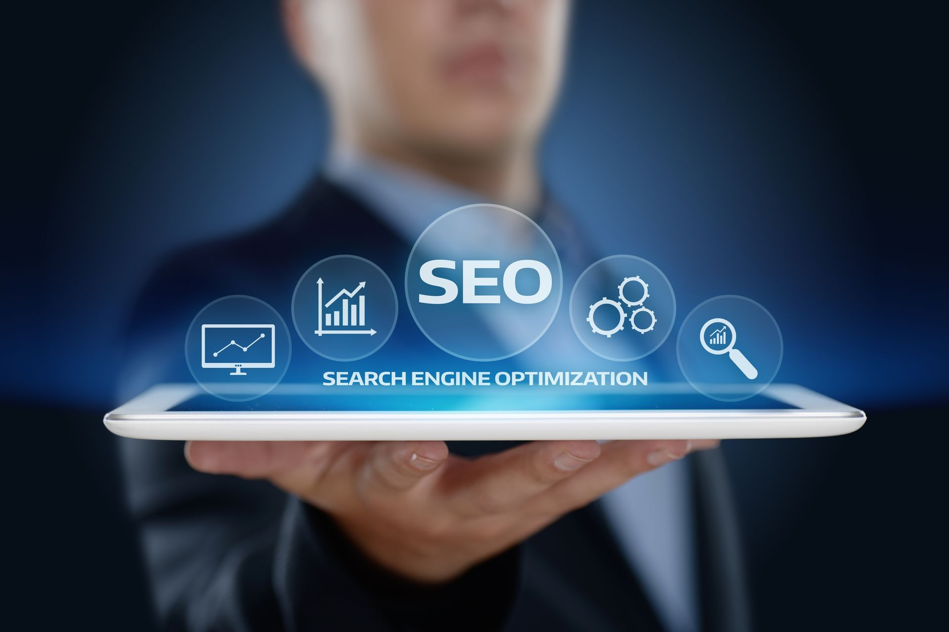 A man is holding a tablet with a screen that says seo search engine optimization.