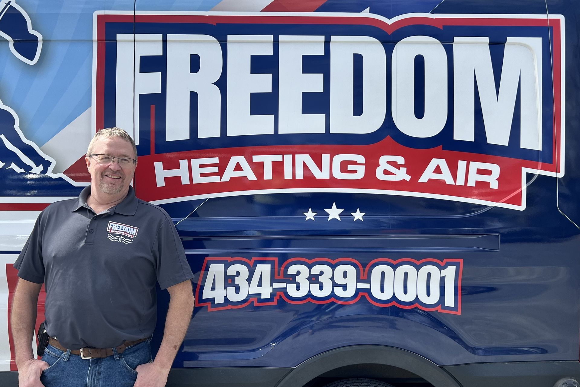 A man is standing in front of a freedom heating and air van.