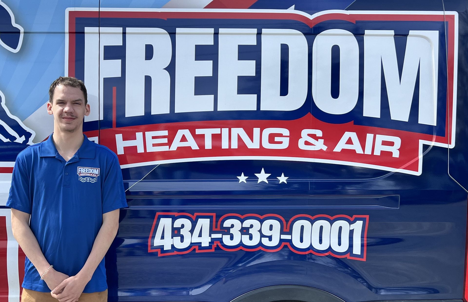 A man is standing in front of a freedom heating and air truck.