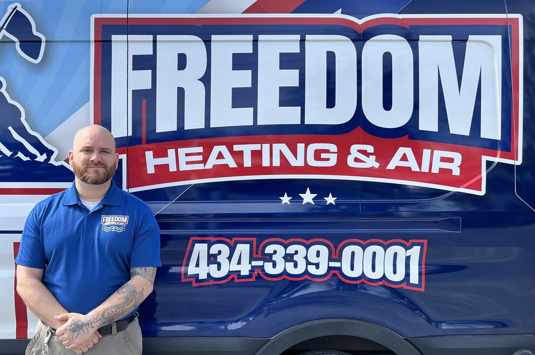 A man is standing in front of a freedom heating and air van.