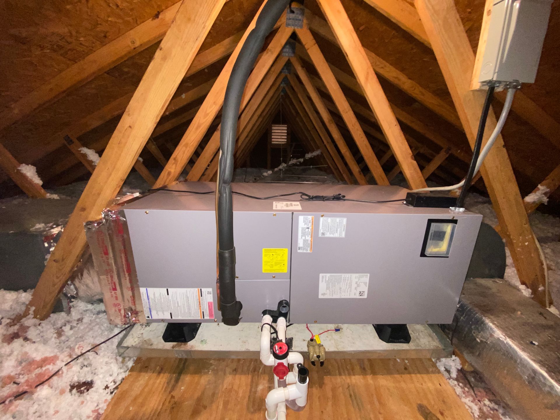 An air conditioner is sitting in the attic of a house.
