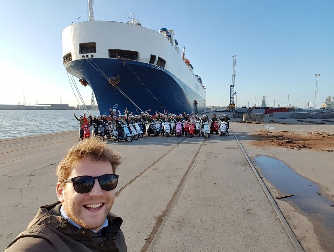 Group of people posing in front of large port cranes.