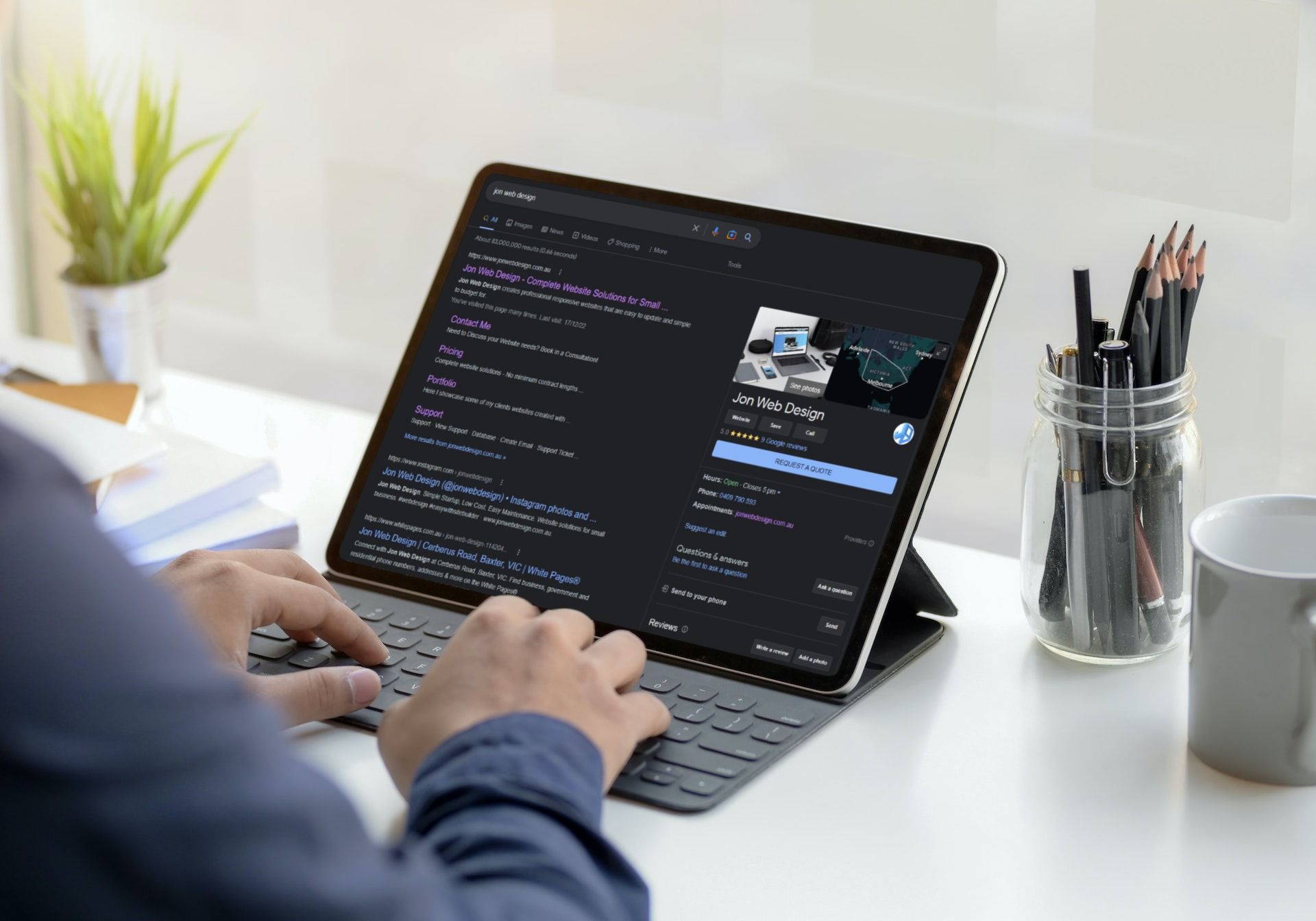 A man is typing on a tablet computer on a desk.