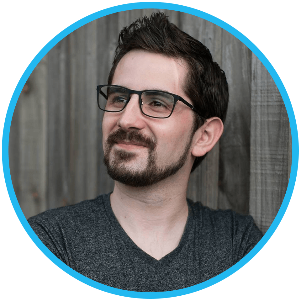 a picture of Jon from Jon Web Design with glasses and a beard is standing in front of a wooden wall .