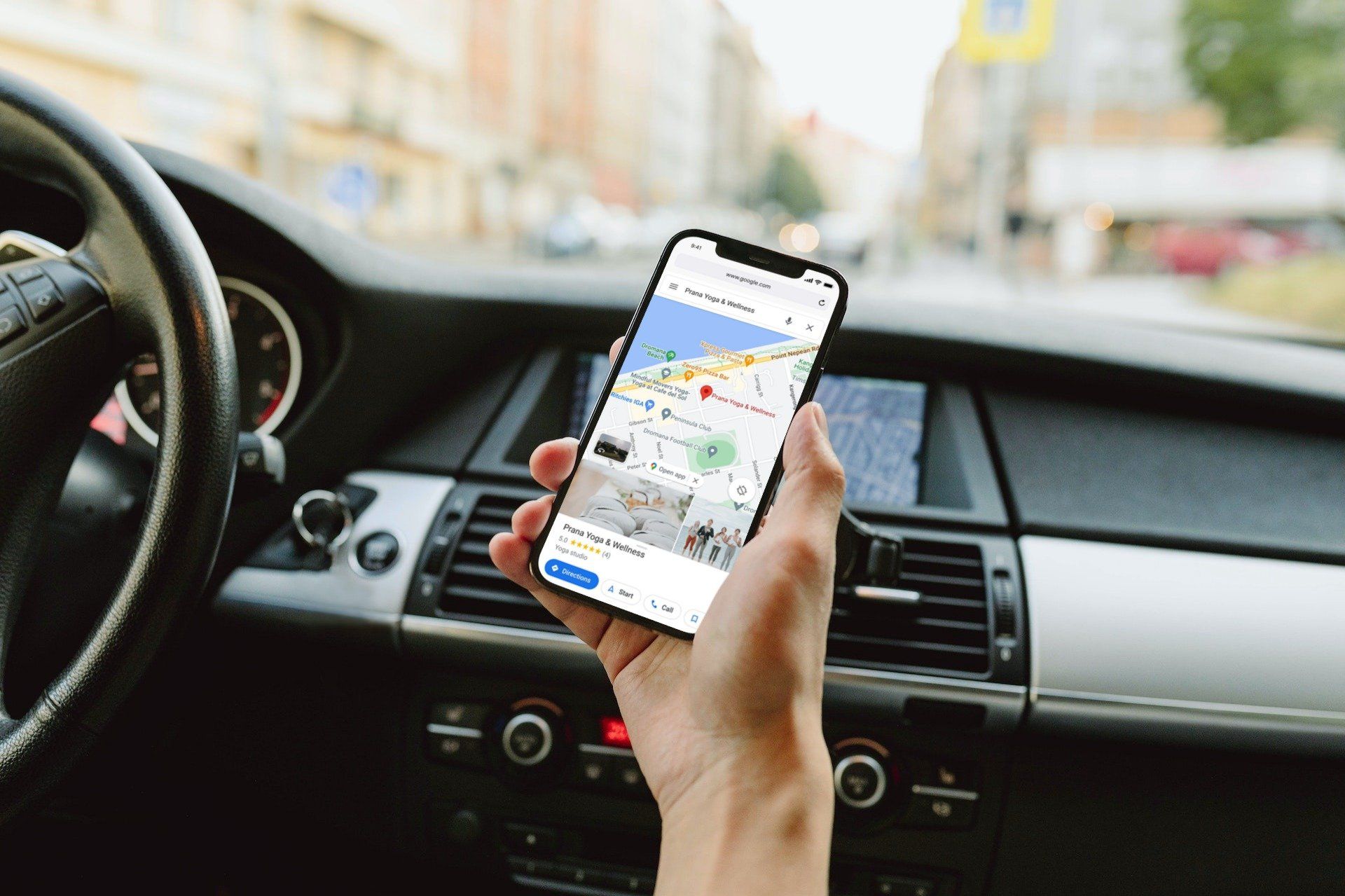 A person is holding a cell phone in their hand in a car.