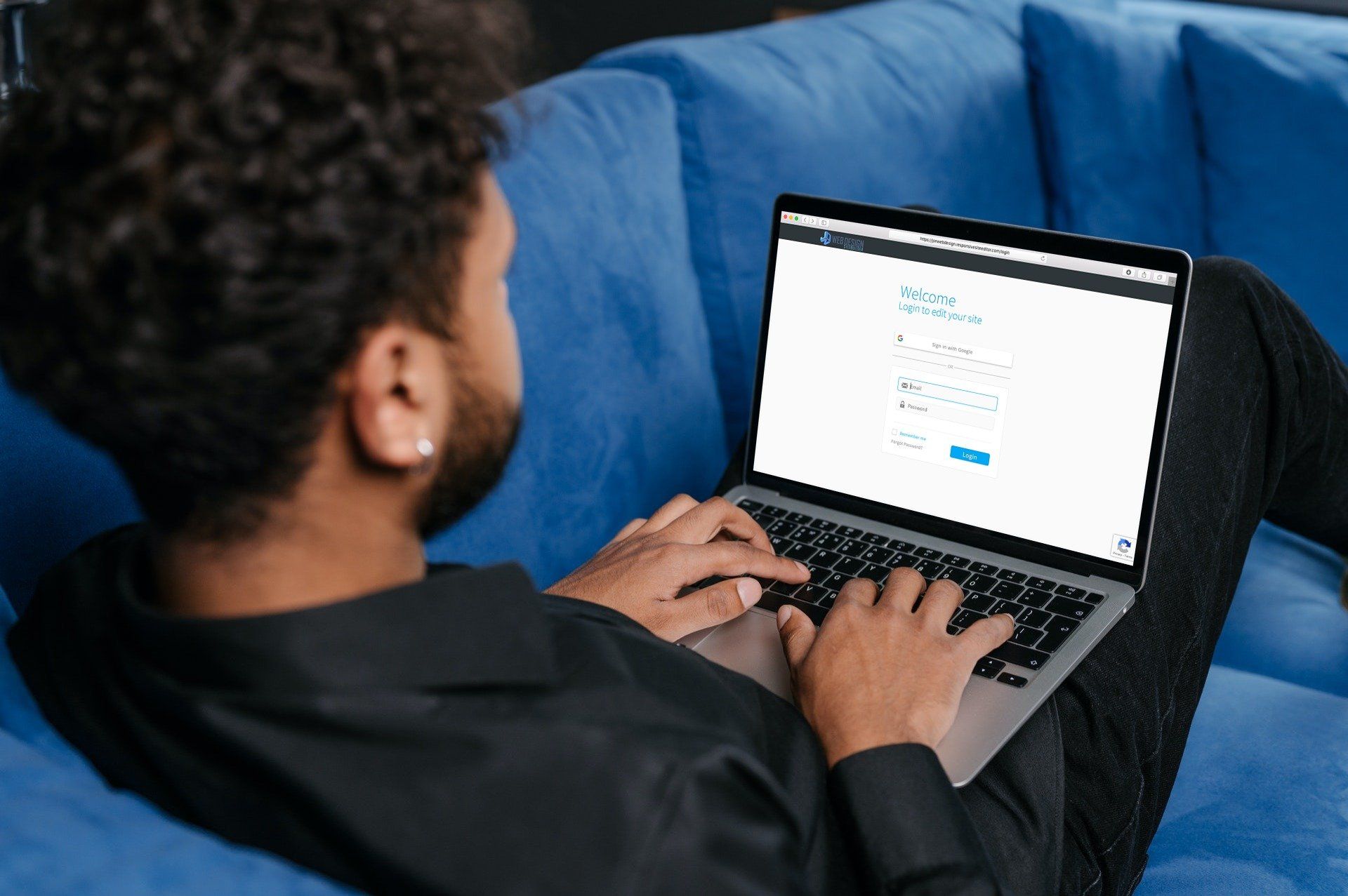 a man is sitting on a blue couch using a laptop computer .