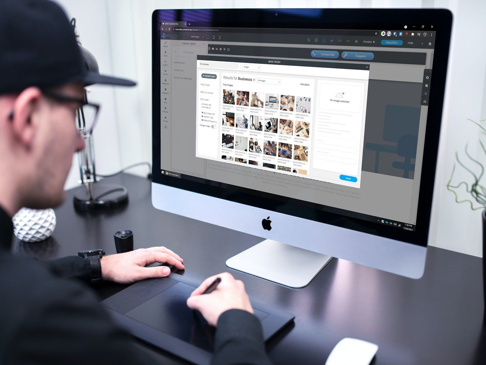 a man is sitting at a desk using an apple computer .