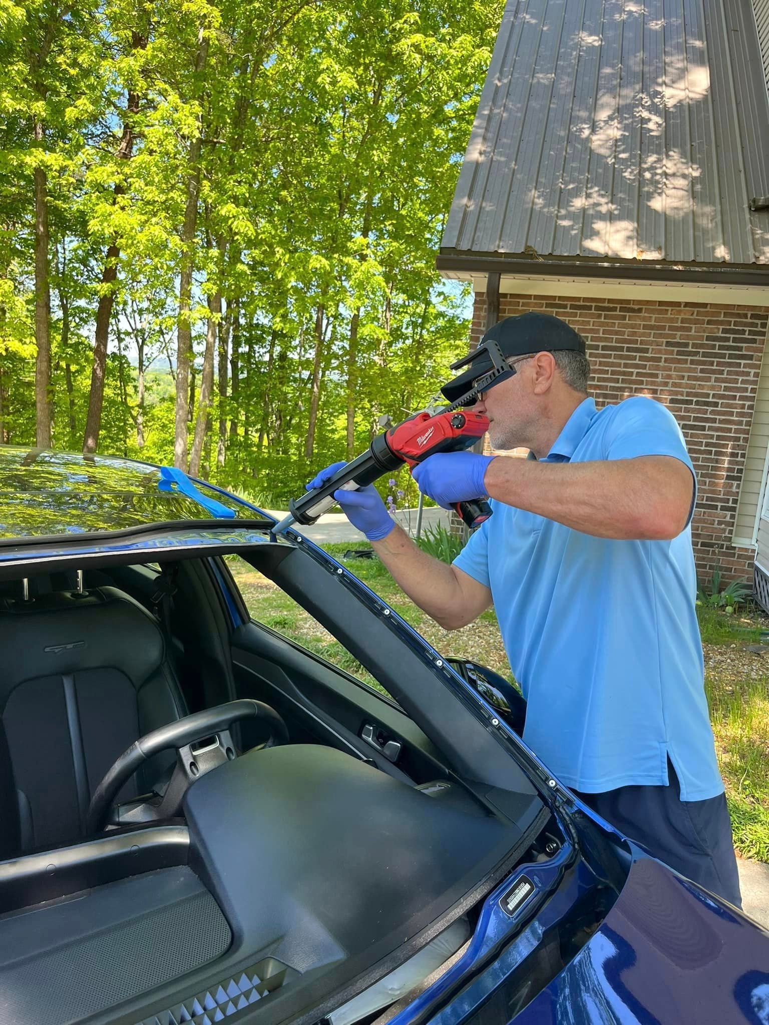 A man is fixing a windshield on a car.