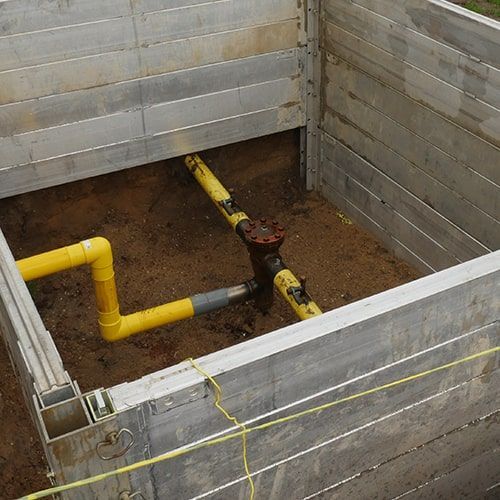 A hole in the ground with yellow pipes coming out of it.