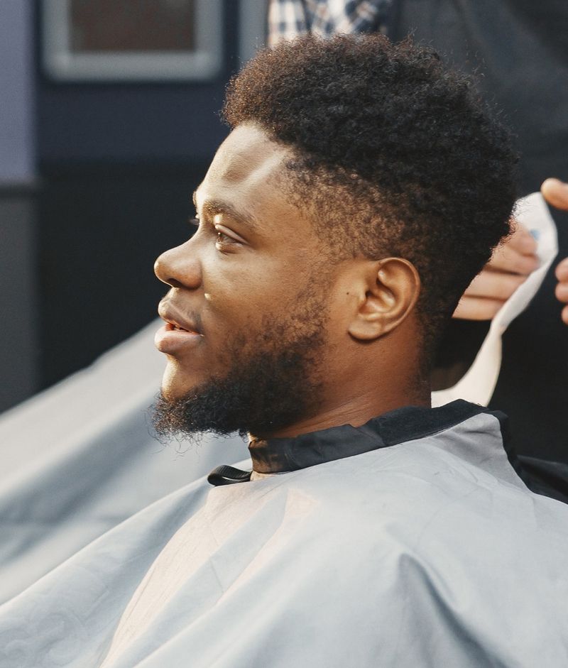 A Man With A Beard Is Getting His Hair Cut By A Barber