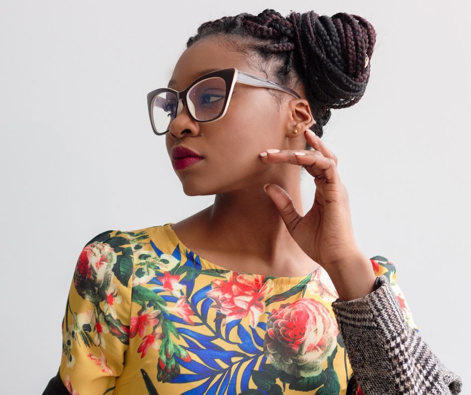 A Woman Wearing Glasses And A Floral Shirt Is Touching Her Face