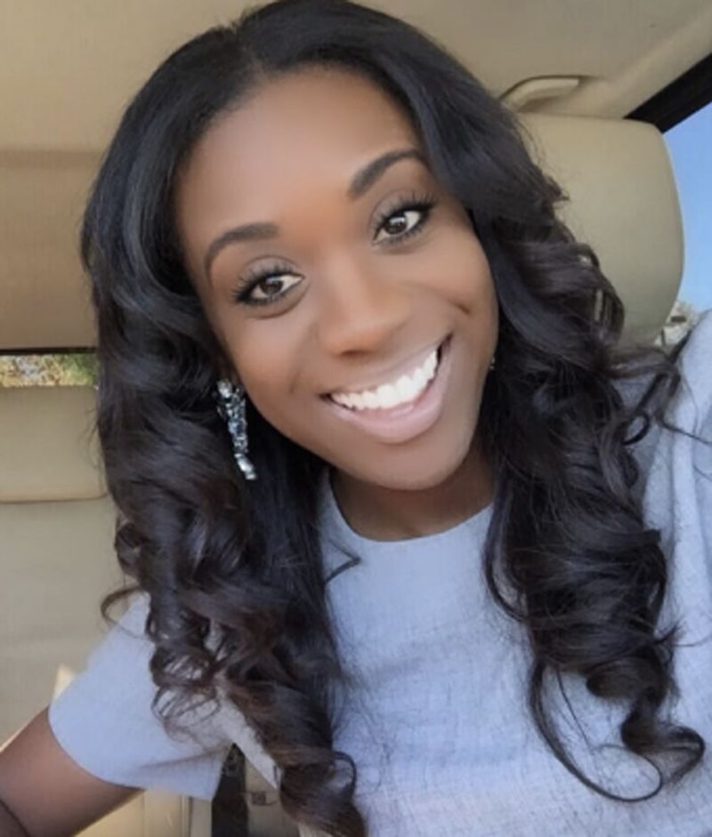 A Woman With Long Curly Hair Is Smiling For The Camera