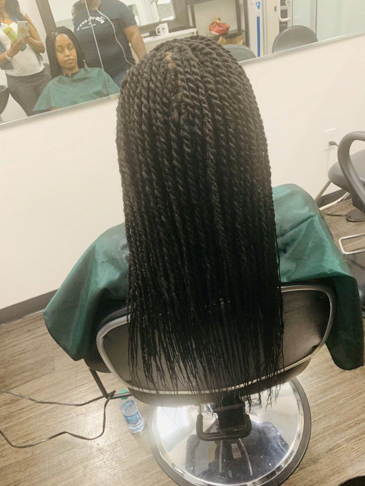 A Woman With Braids Is Sitting In A Chair In Front Of A Mirror
