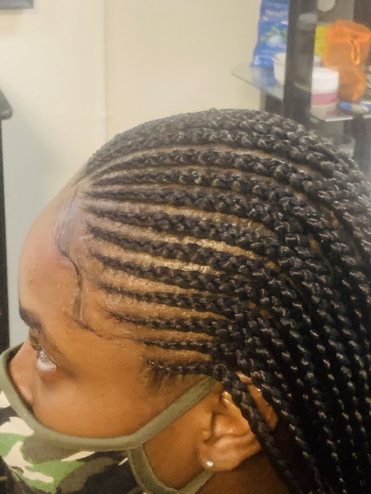 A Woman With Braids On Her Head Wearing A Mask