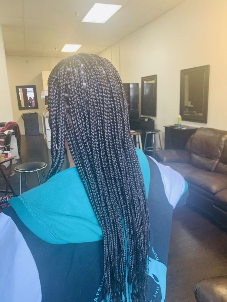 A Woman With Braids In Her Hair Is Sitting In Salon