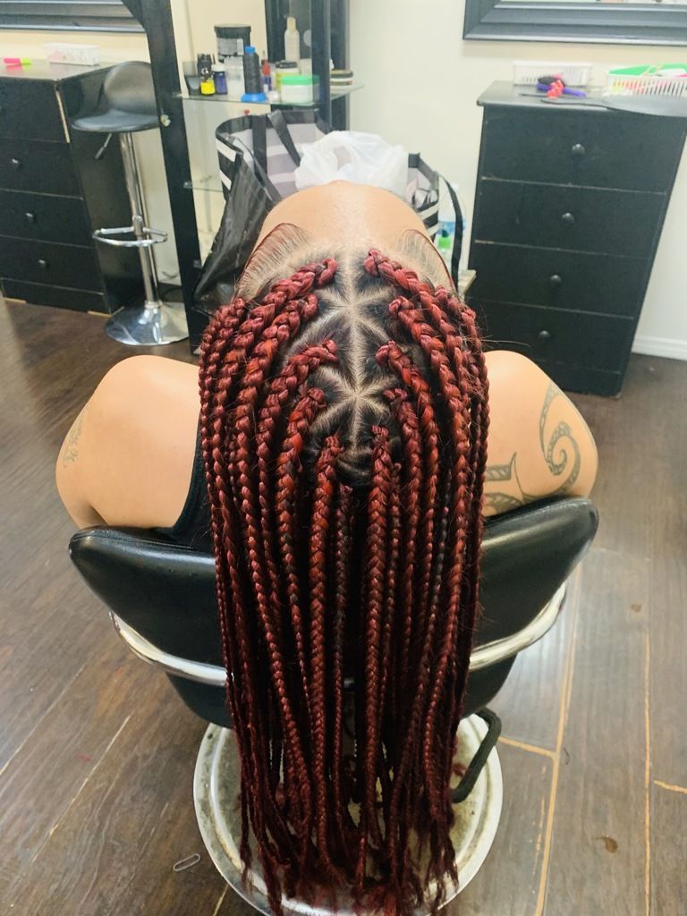 A Woman Is Sitting in A Chair with Braids In Her Hair