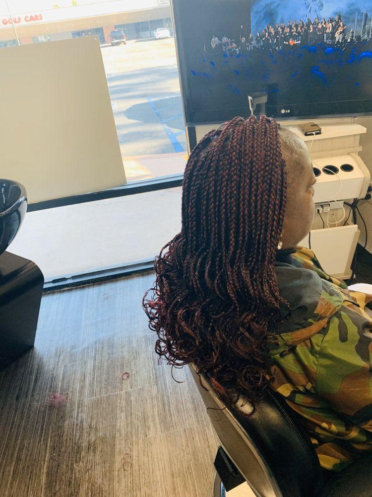 A Woman Is Sitting In A Chair With Her Hair Braided In A Salon
