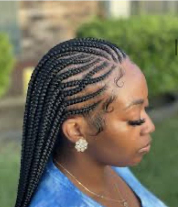 Woman with long black braided hairstyle, wearing a blue shirt, and earrings.