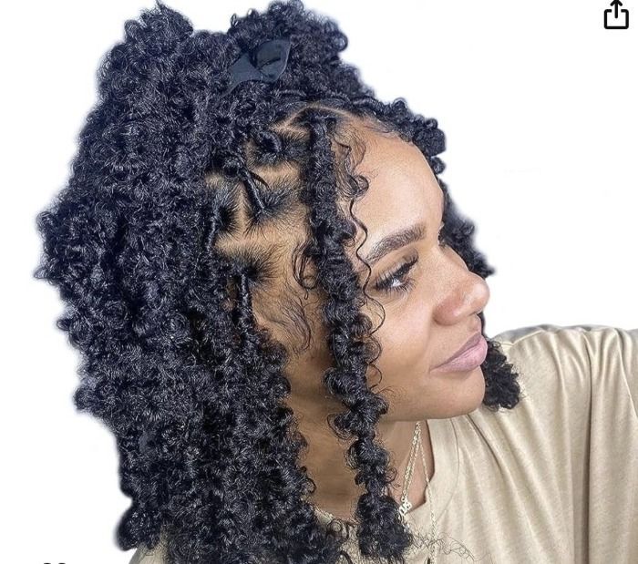Woman with butterfly locs hairstyle, side profile, wearing a beige top.