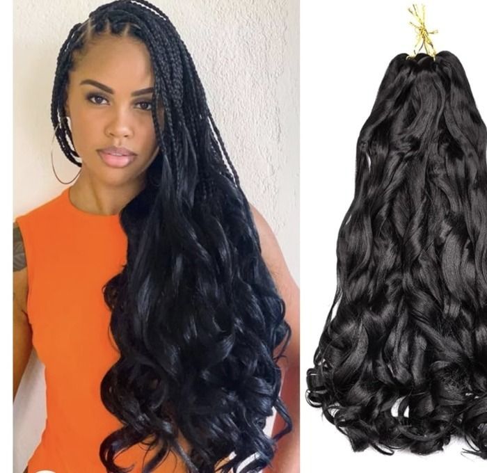 Woman with long black braids and wavy extensions, wearing an orange top.