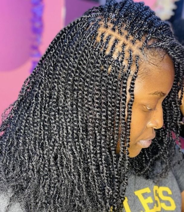 Woman with long, black micro-twists hairstyle, some parted and laid.