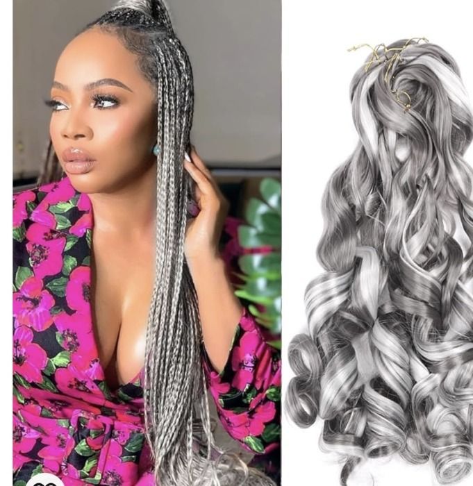 Woman with long black braids and wavy extensions, wearing an orange top.