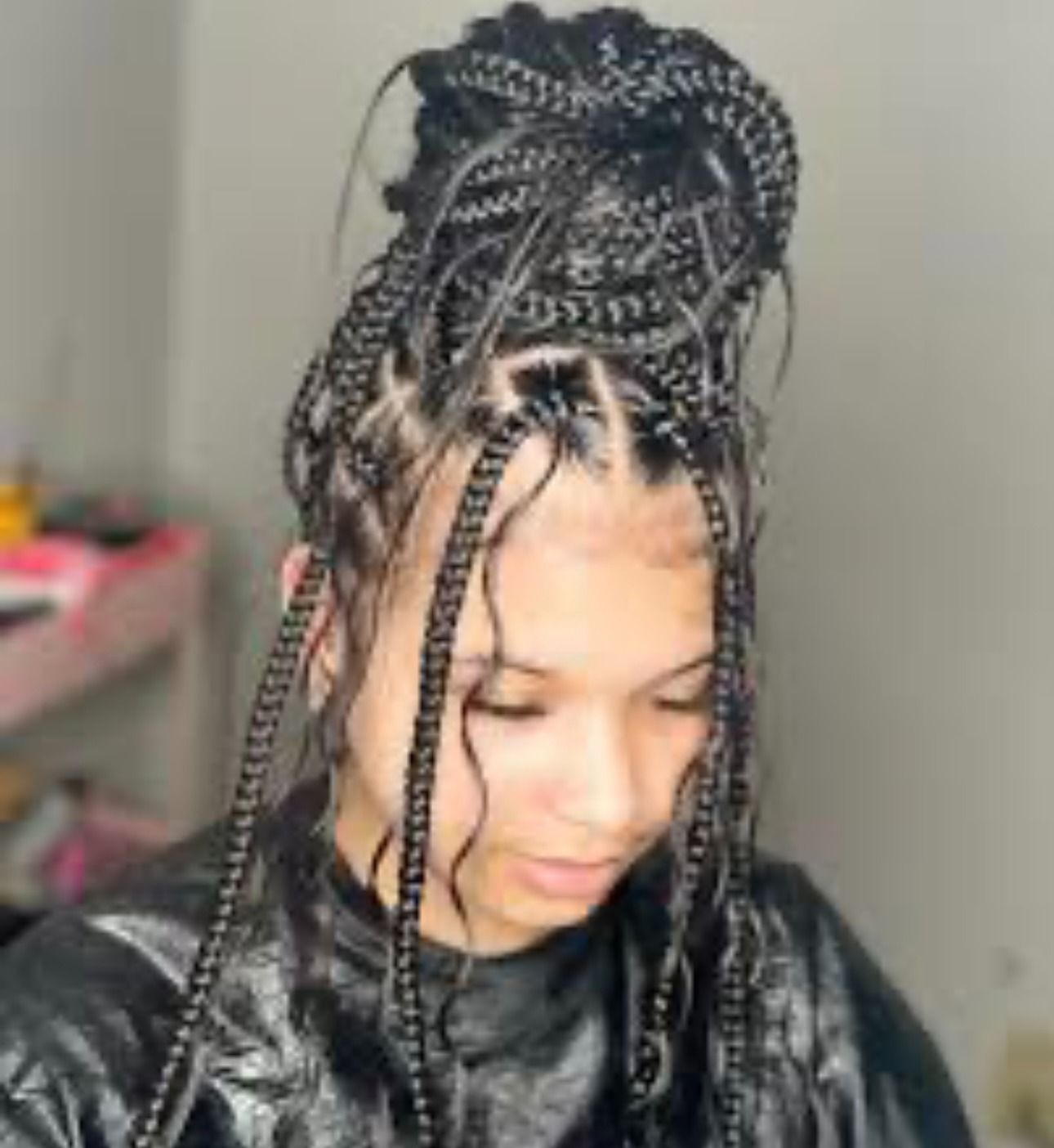 Woman with box braids pulled up in a high bun with face-framing strands.