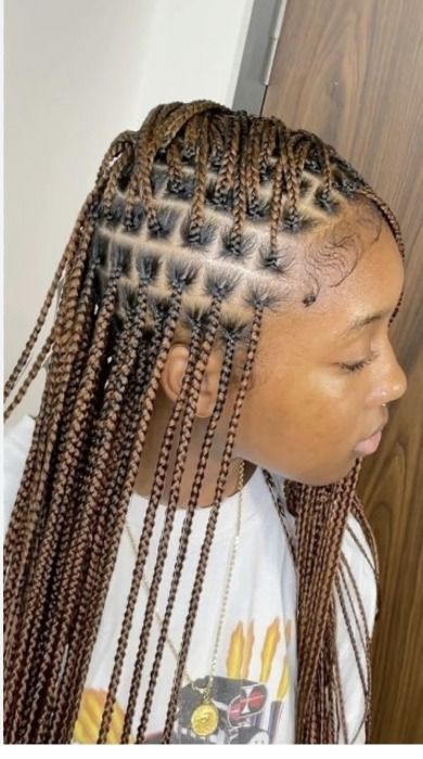 Woman with brown braided hair, some styled in a geometric pattern on the side of her head.