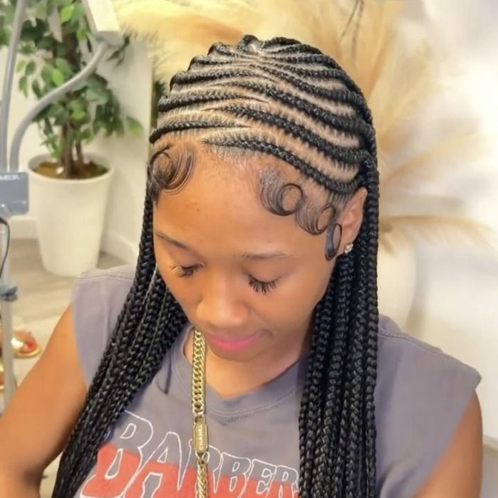 Woman with cornrow braids and styled baby hairs, wearing a gray shirt and gold chain.