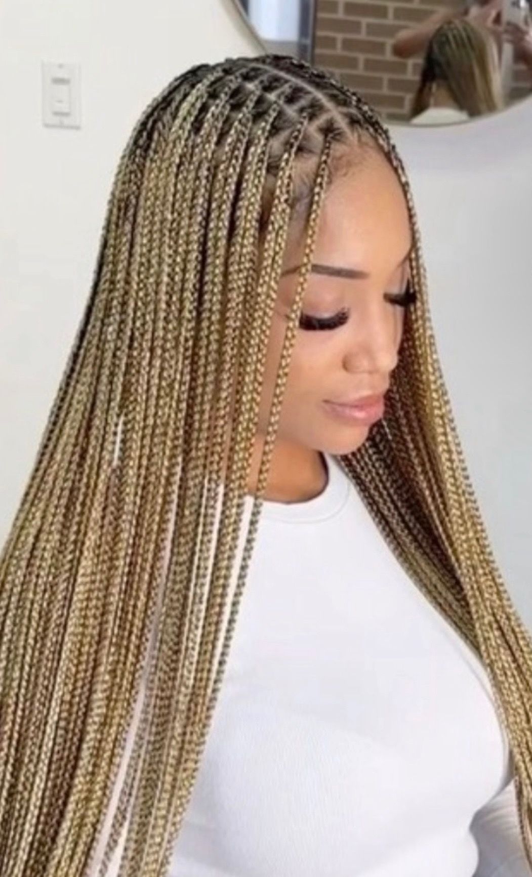 A woman with braids in her hair is sitting in front of a door.