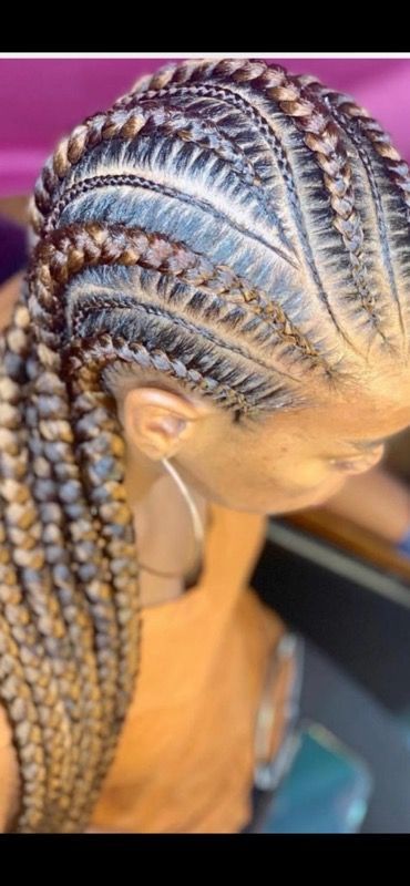 A woman with braids in her hair is wearing hoop earrings.