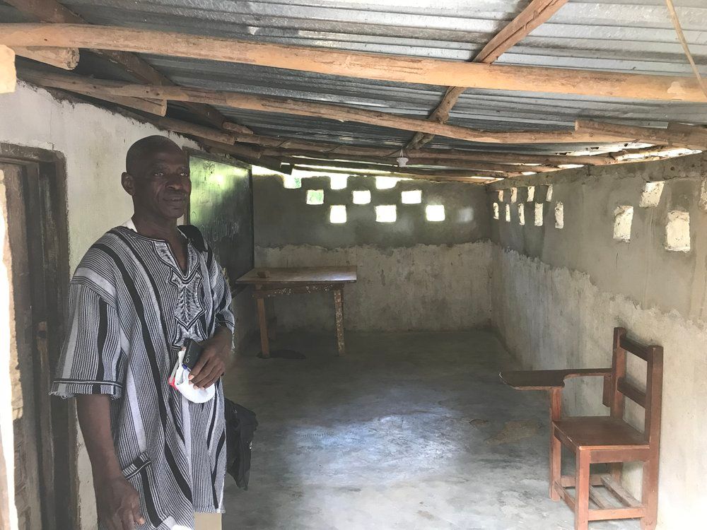 A man is standing in an empty room with a table and chairs.