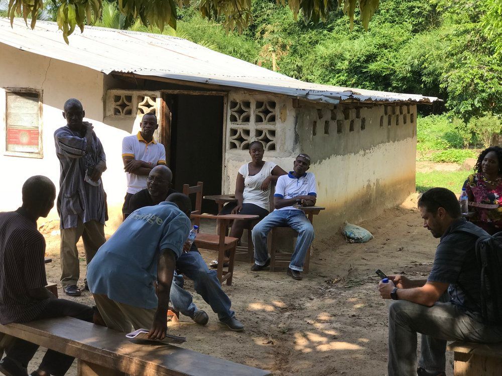 A group of people are sitting on benches outside of a building.