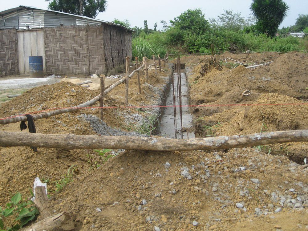 A wooden fence is surrounded by a pile of dirt and rocks.