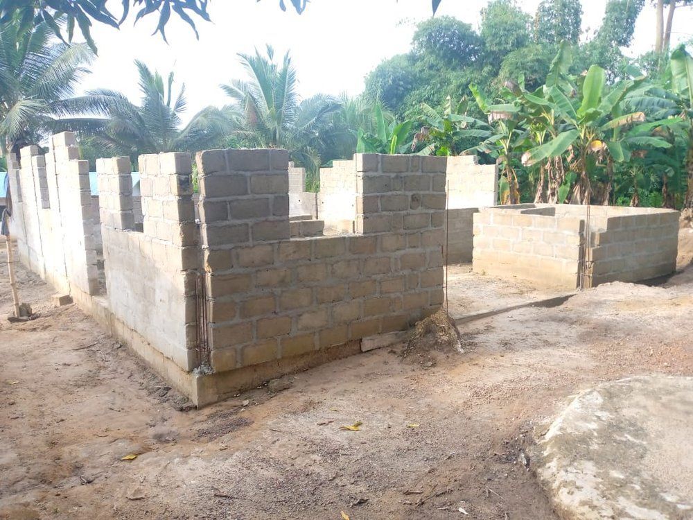 A row of brick walls are being built in a dirt field.