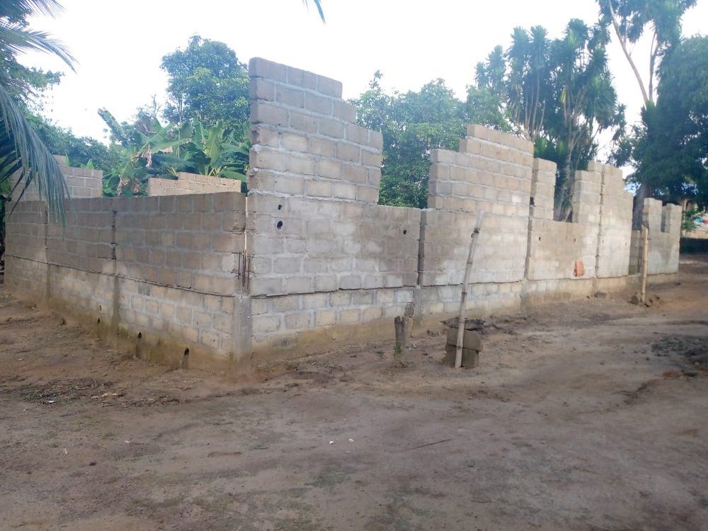 A brick wall is being built in a dirt field