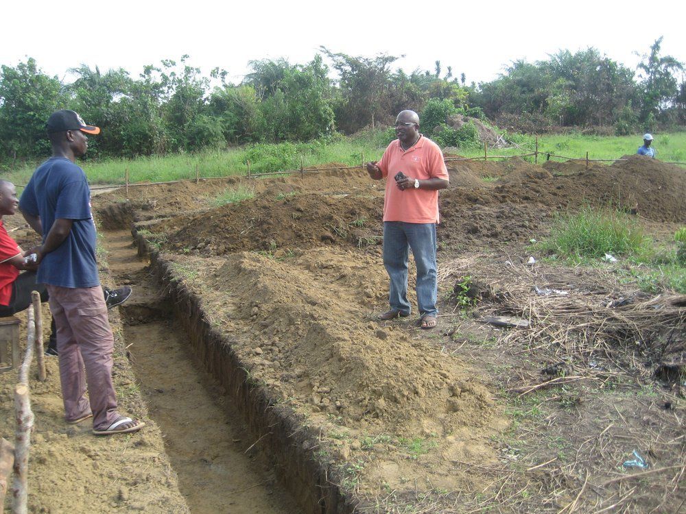 A man in an orange shirt is standing in the dirt