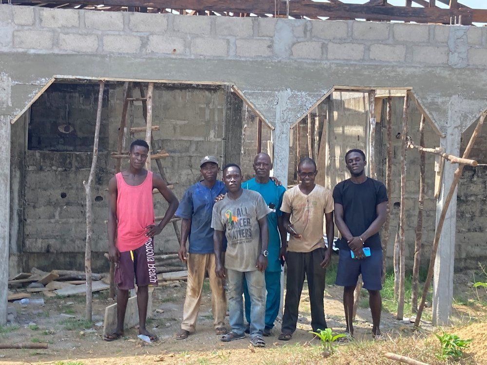 A group of men are standing in front of a building under construction.