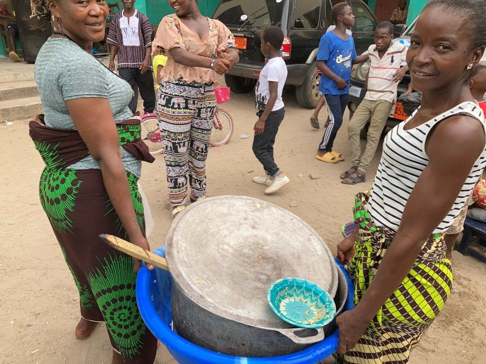 A group of people are standing around a large pot.