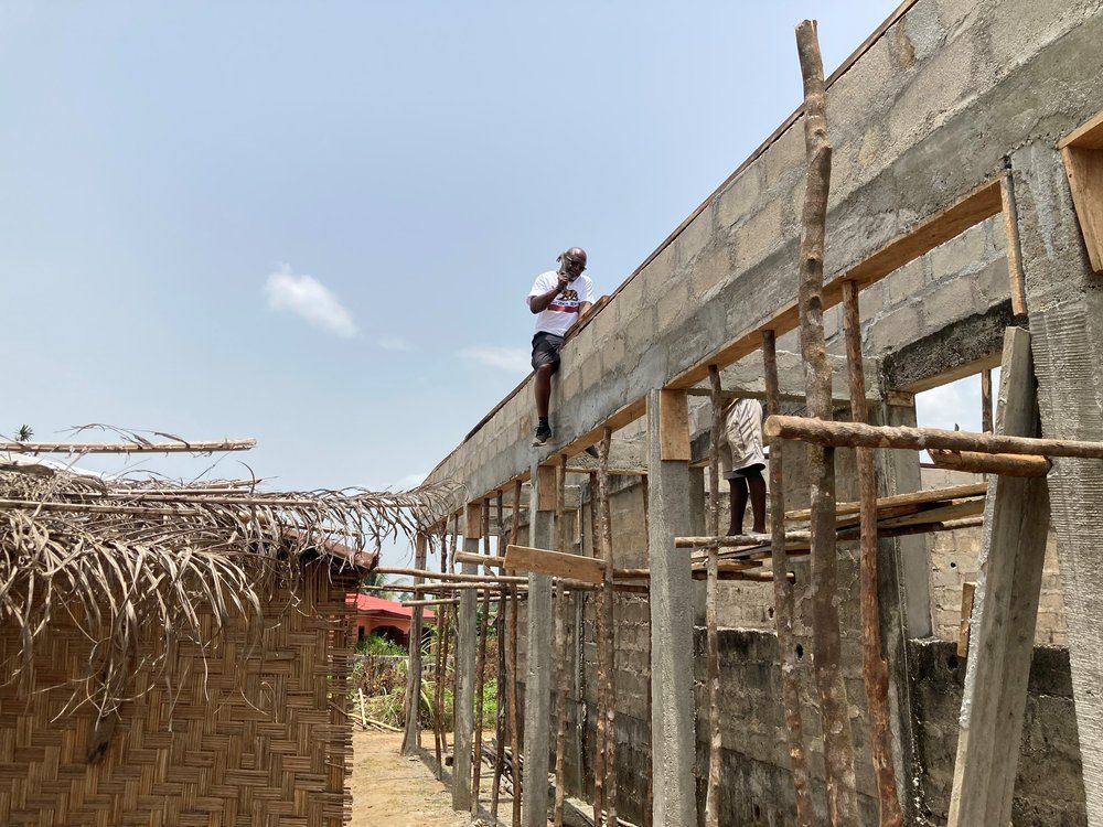 A man is standing on top of a building under construction.