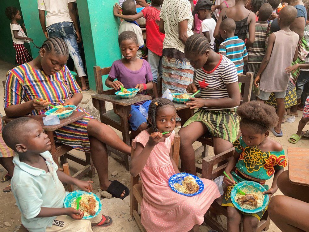 A group of children are sitting in chairs eating food.